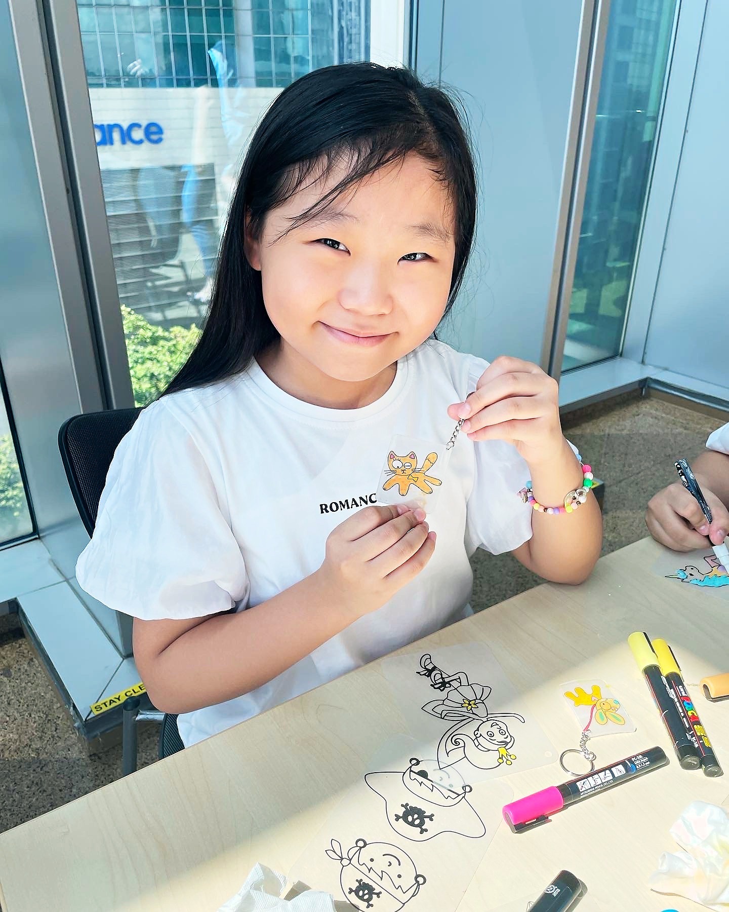 Child showing a handmade keychain at the craft table
