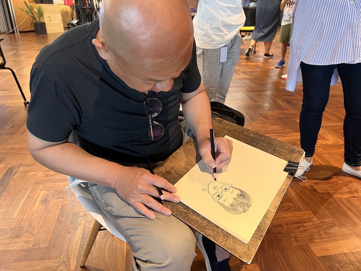 Caricature artist drawing a portrait on paper