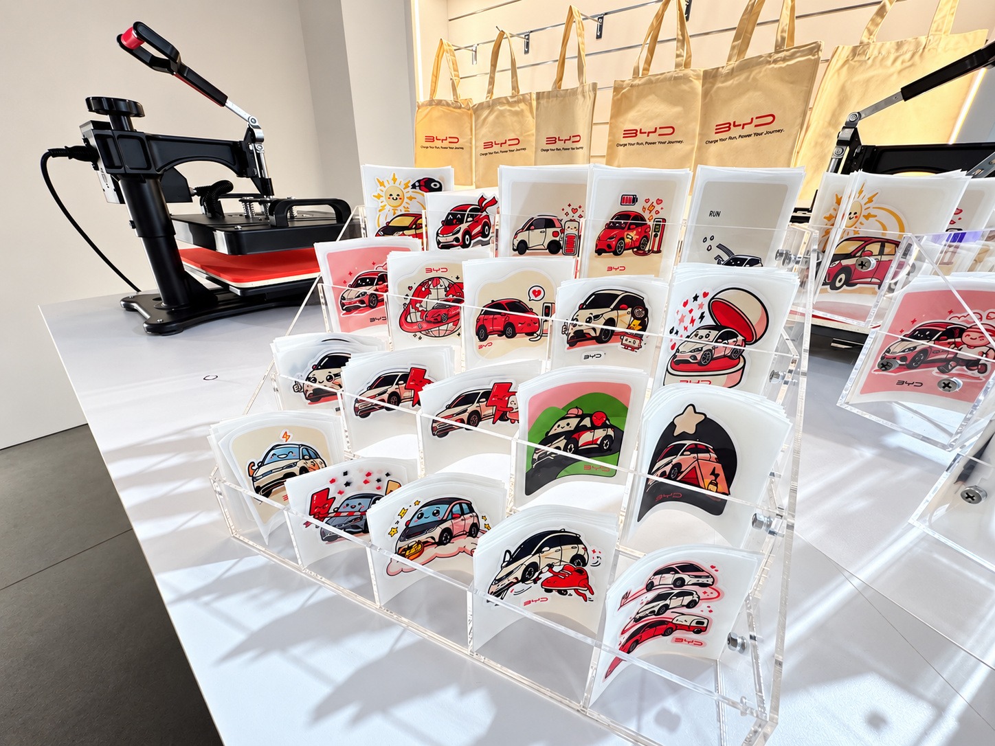 Printed transfer sheets beside a tote bag heat press